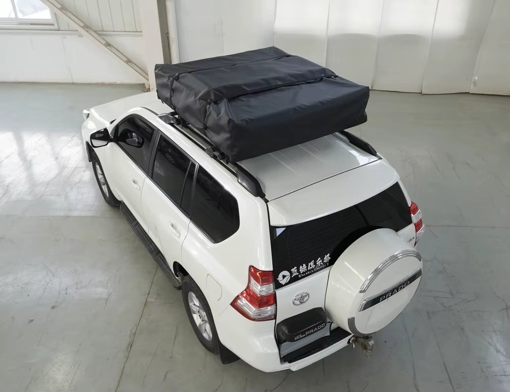 Folded rooftop tent secured to the roof of an SUV for vehicle-based camping