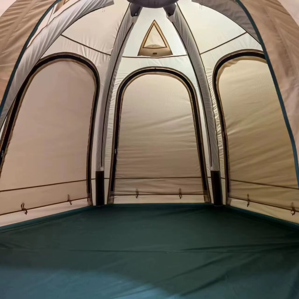 Interior of a beige camping tent showing arched inner doorways, mesh panels, and a green floor.