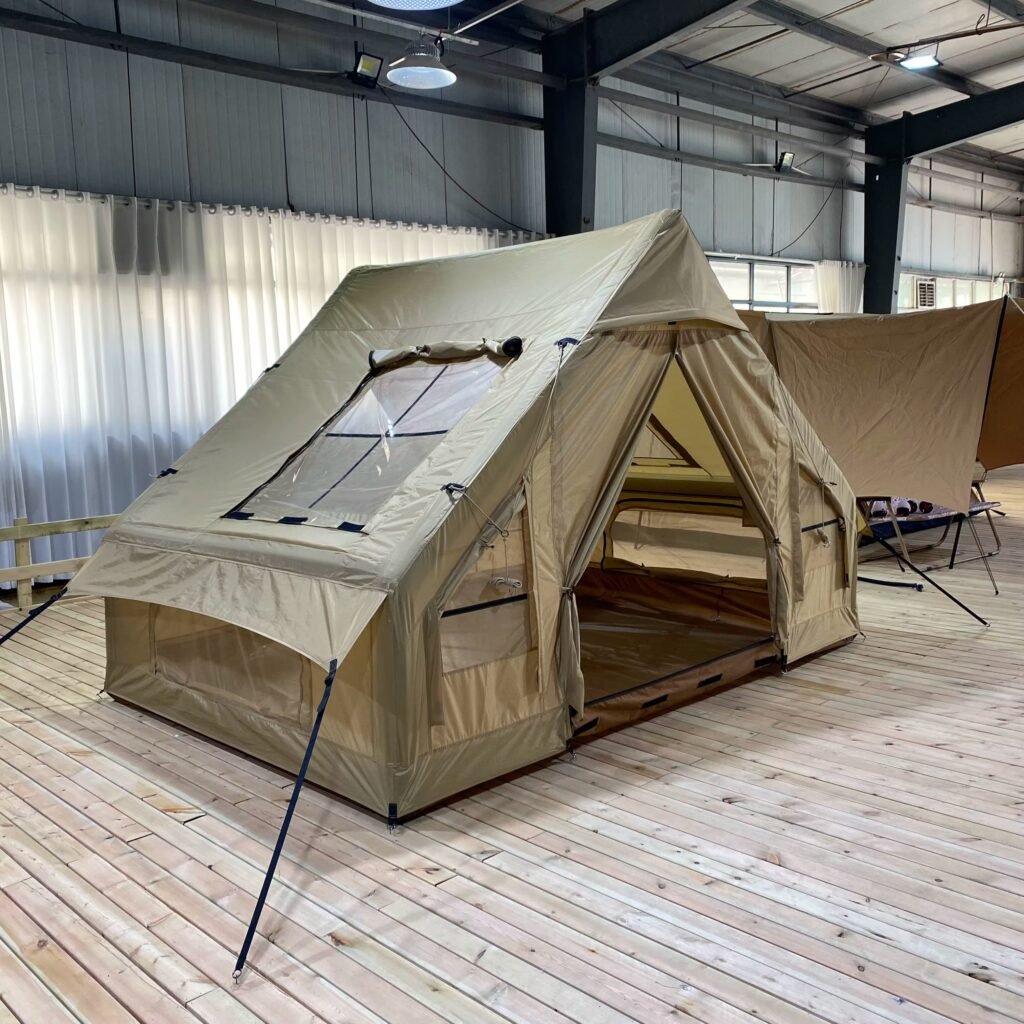 Angled view of a beige inflatable tent with the entrance open and guy lines attached.