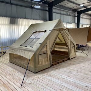 Angled view of a beige inflatable tent with the entrance open and guy lines attached.