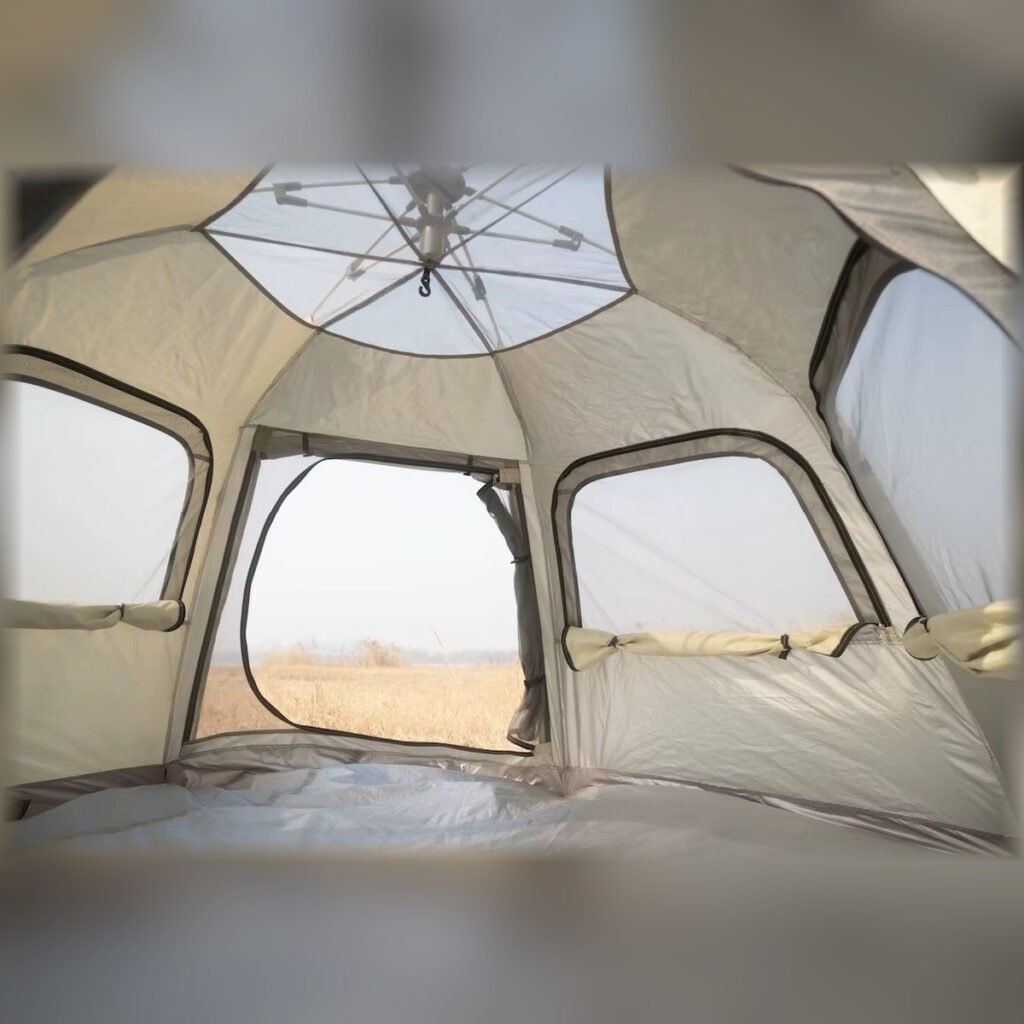 Interior view of a beige pop-up camping tent showing the roof frame, mesh windows, and floor.