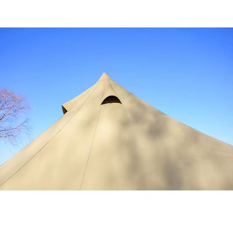 Exterior view of the covered ventilation opening near the peak of a beige teepee tent.