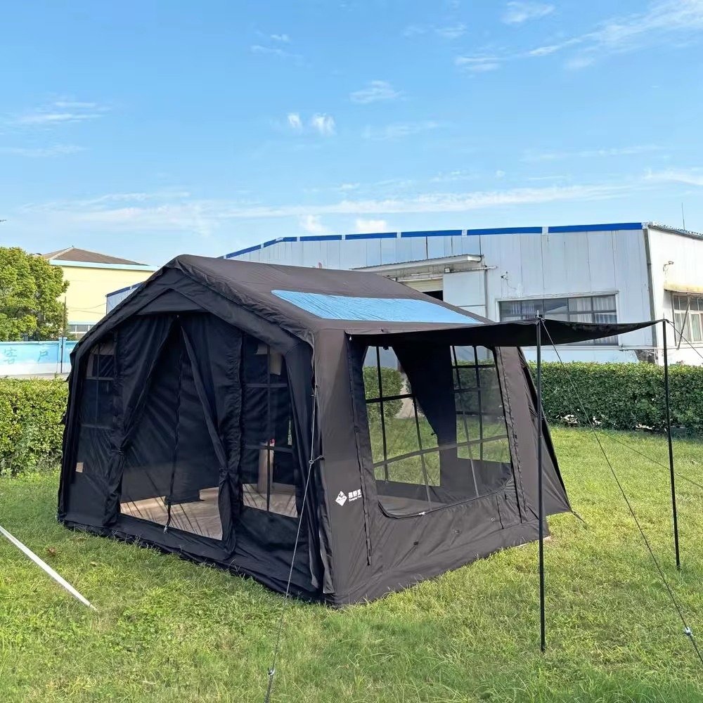 Black inflatable cabin tent with mesh windows and an extended front awning set up on grass.