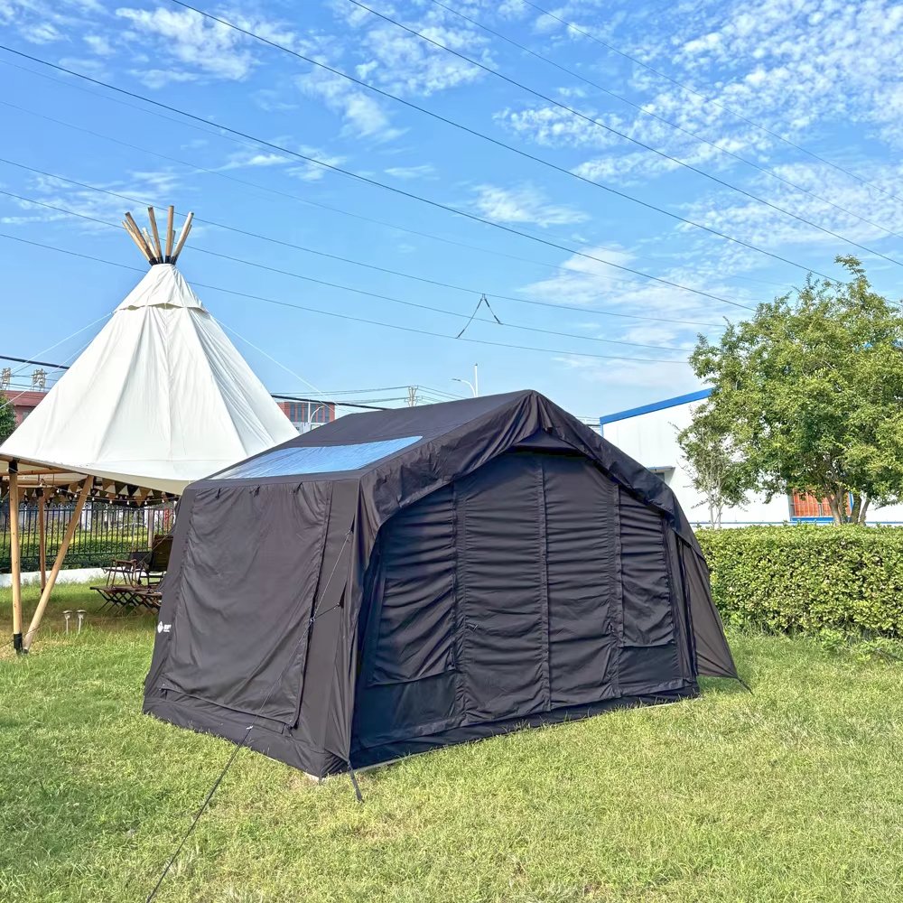 Dark tent set up on a grassy lawn beneath a blue sky