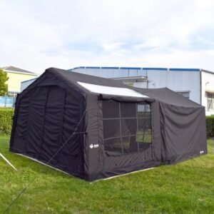 Black inflatable tent with an extended side awning and guy lines on a grassy campsite.