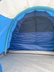 Tent interior showing a zippered inner door with a dark upper panel and blue fabric below.