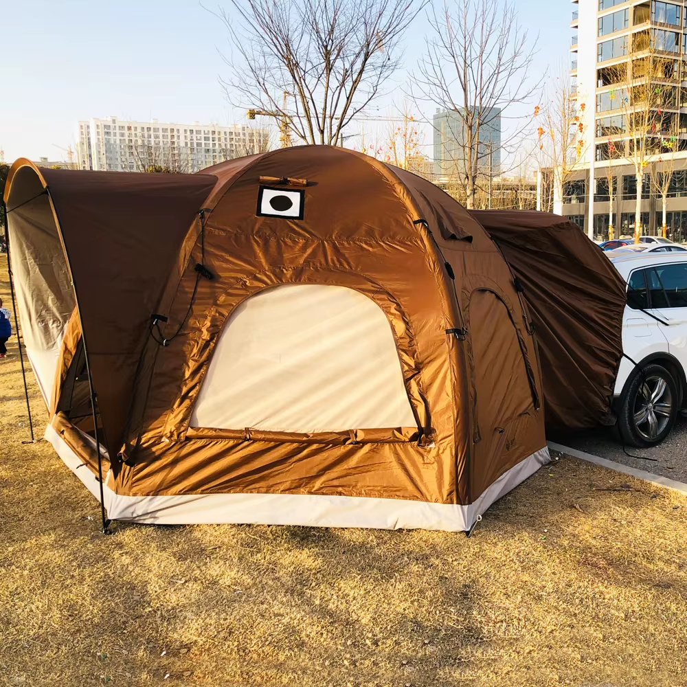Brown and beige camping tent beside a parking area and city buildings