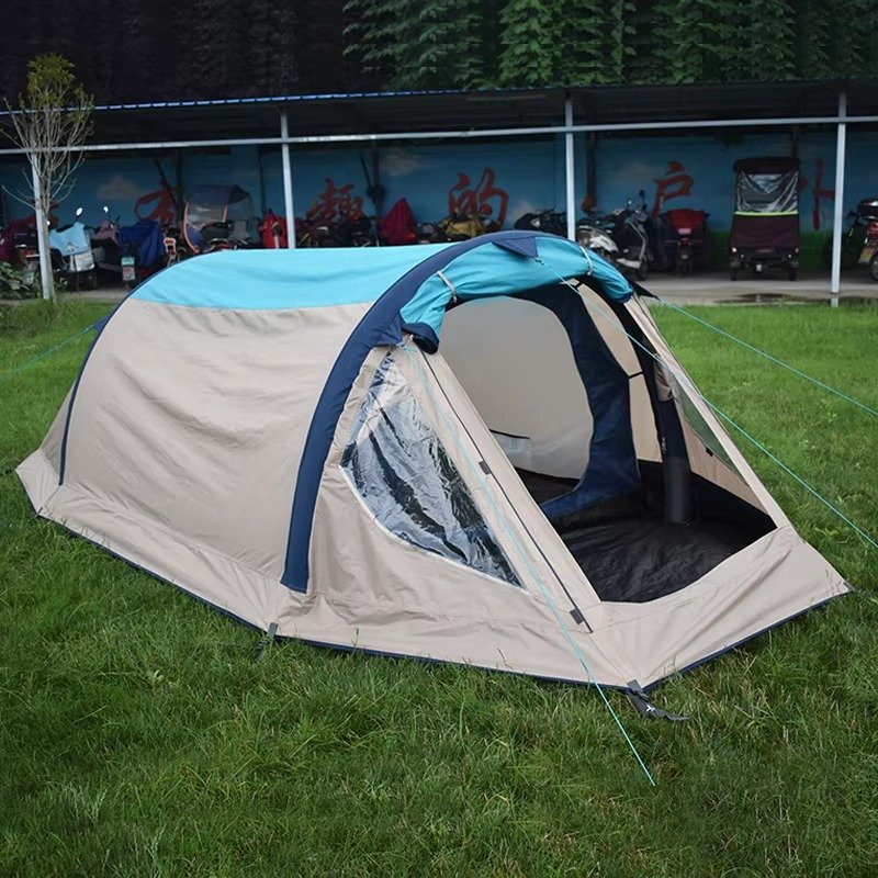 Gray and blue inflatable camping tent with an open front entrance set up on grass.