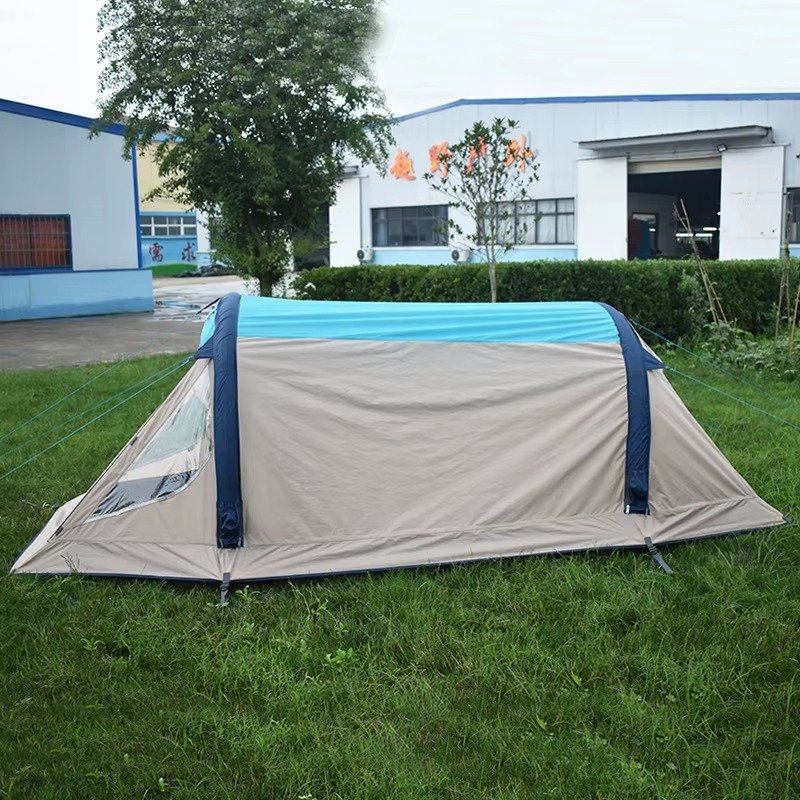 Side profile of a gray and blue inflatable camping tent set up on grass.