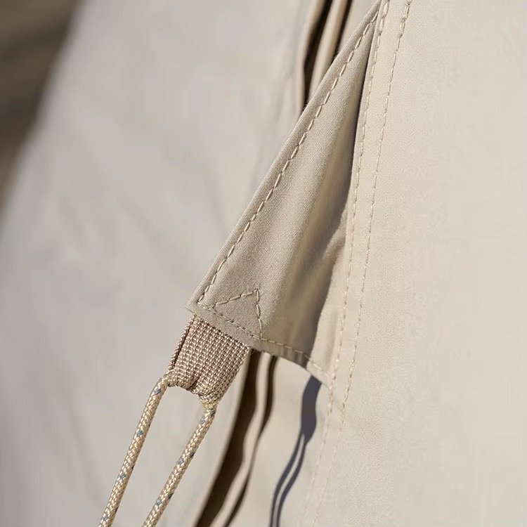 Close-up of a guyline attached to the reinforced fabric of a beige teepee tent.